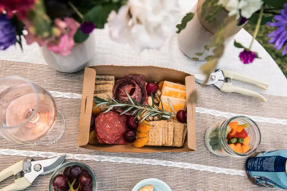 Picnic basket spread on a table with flowers and drinks